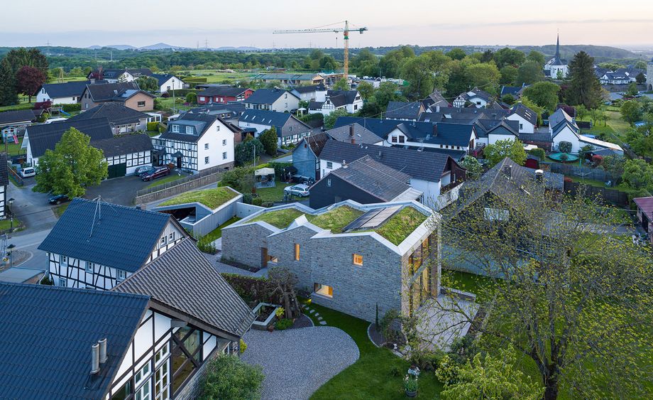 Luftaufnahme des mehrteiligen, langgestreckten Gebäuderiegels mit Dachbegrünung