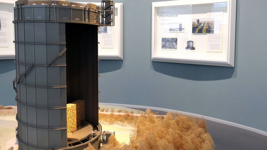 Ein Modell vom Gasometer Oberhausen, im Hintergrund sind Infotafeln zu sehen. 