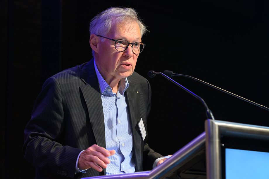 Ein Mann steht an einem Pult und spricht in ein Mikrofon.