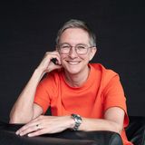 Halbkörper-Portrait, sitzend vor schwarzem Hintergrund