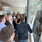 Eine Gruppe Menschen im Gespräch vor Schautafeln mit Fotos