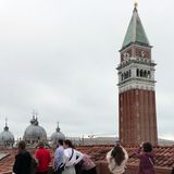 Ein hoher Turm wird von einigen Personen fotografiert, der Himmel ist bewölkt.