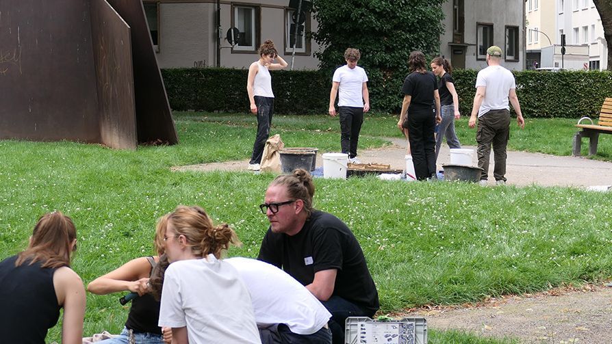 Junge Leute arbeiten in einem Park an Projekten zum Thema "Lehmbau" und erarbeiten Lehmmauern und Lehmziegel.