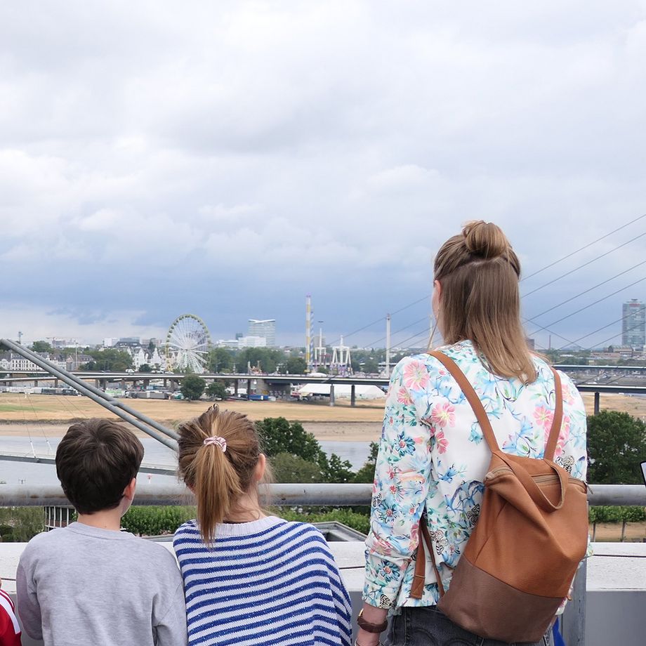 Personen stehen mit dem Rücken zur Kamera gewandt und betrachten eine urbane Skyline.
