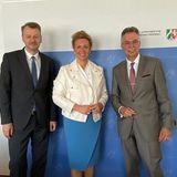 Drei Personen vor einer blau-weißen Wand stehend