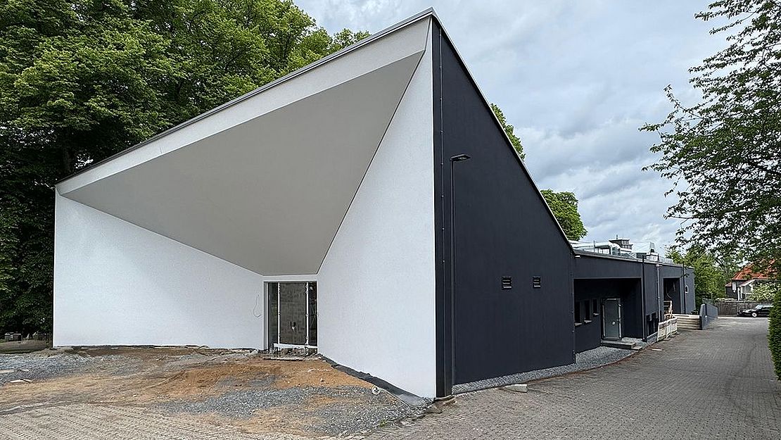 Regionale Haus der Kulturen Länglicher Gebäudetrakt durch ein trichterförmig eingeschnittenes und ganz in Weiß gehaltenes Eingangsgebäude erweitert