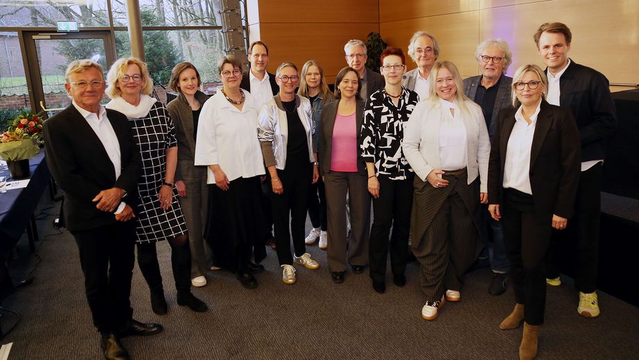 Gruppenbild mit 15 Personen in einem Tagungsraum stehend