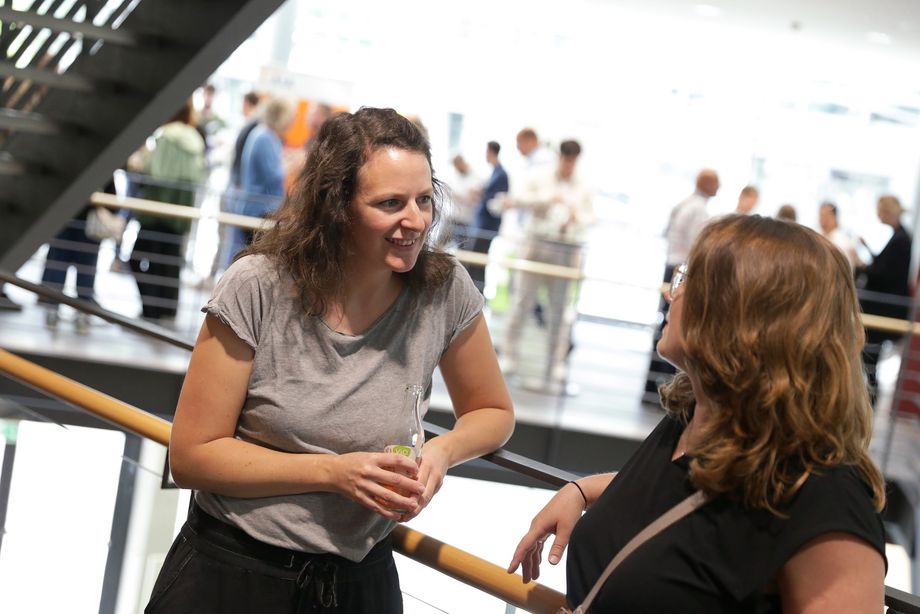 Zwei Frauen unterhalten sich angeregt, im Hintergrund sind mehrere Personen stehend zu sehen. - Foto: Ingo Lammert/Architektenkammer NRW
