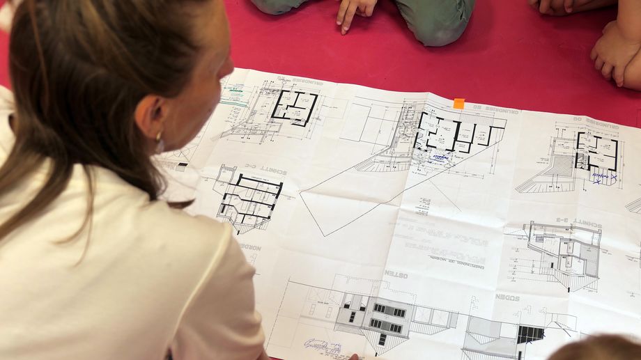 Personen betrachten einen Bauplan, der auf dem Boden ausgelegt ist.