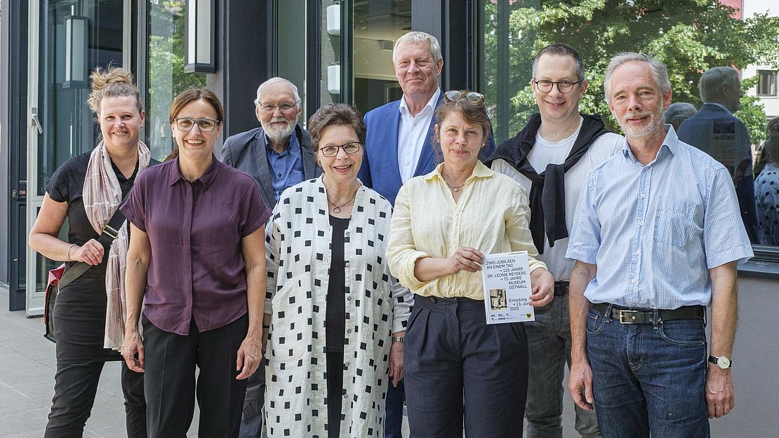 Auftakt_Leonie-Reygers-Lounge_BKA-NRW_Gruppenbild_Foto-Detlef-Podehl Zur Veranstaltung im BKA NRW sprachen (v.l.): Dr. Kristina Kratz-Kessemeier (Berlin), Prof. Dr. Sonja Hnilica (TU Dresden), Klaus Fehlemann (Förderverein Baukunstarchiv NRW), Dr. Gisela Framke (Dortmund), Jörg Stüdemann (Stadtdirektor und Kulturdezernent, Dortmund), Dr. Ruth Hanisch (TU Dortmund), Benjamin Sieber (Vorsitzender Freunde des Museums Ostwall e. V.) und Prof. Dr. Wolfgang Sonne (Baukunstarchiv NRW).- Foto: Detlef Podehl - Die Personen stehen zusammen und lächeln. Im Hintergrund der Personengruppe sind die Fenster des Baukunstarchivs NRW, in denen sich Bäume aus der anliegenden Parkanlage spiegeln.
