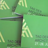 Grüne Broschüren liegen zerstreut auf einem Tisch.