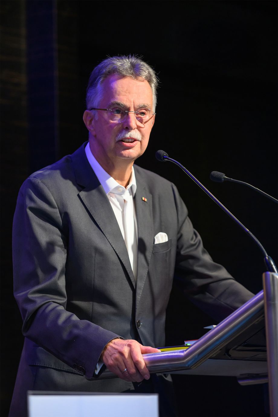 Ein Mann steht an einem Pult und spricht in ein Mikrofon.