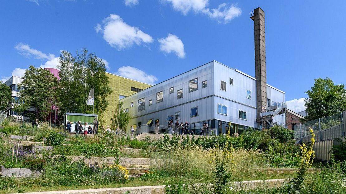 Der BOB Campus in Wuppertal - Archivbild: Tag der Landschaftsarchitektur 2024. - Foto: Mathias Kehren/Architektenkammer NRW Der BOB Campus in Wuppertal: Zu sehen ist eine Grünanlage mit verschiedenen bunten Pflanzen, im Hintergrund erkennt man mehrere Gebäude, die den sogenannten BOB Campus darstellen. - Archivbild: Tag der Landschaftsarchitektur 2024. - Foto: Mathias Kehren/Architektenkammer NRW