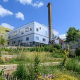 Der BOB Campus in Wuppertal: Zu sehen ist eine Grünanlage mit verschiedenen bunten Pflanzen, im Hintergrund erkennt man mehrere Gebäude, die den sogenannten BOB Campus darstellen. - Archivbild: Tag der Landschaftsarchitektur 2024. - Foto: Mathias Kehren/Architektenkammer NRW