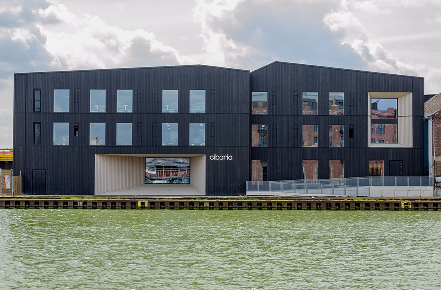 Gewerbegebäude mit dunkler Holzfassade, am Wasser gelegen